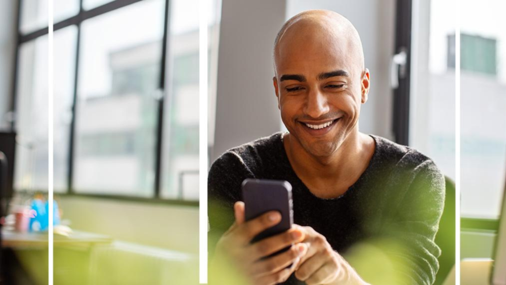 Mann schaut auf Handy und lächelt